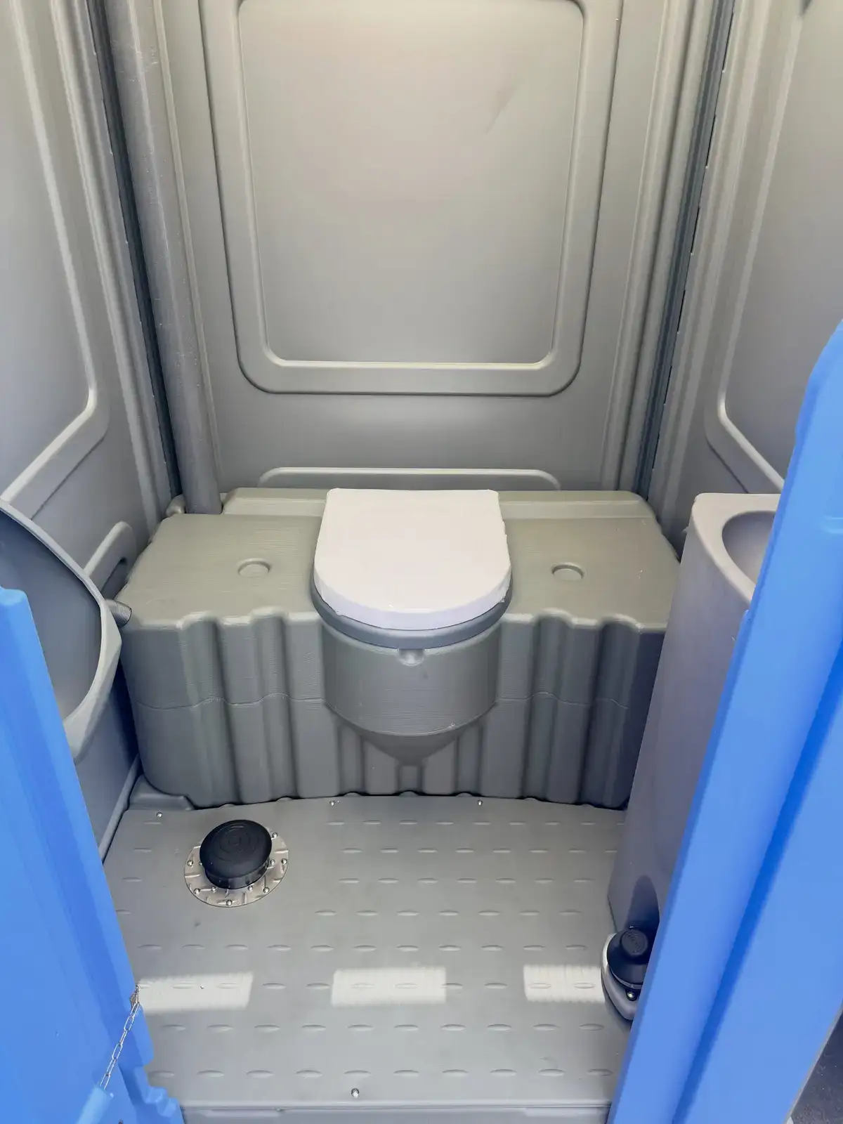 Gray portable toilet interior with seat and textured floor