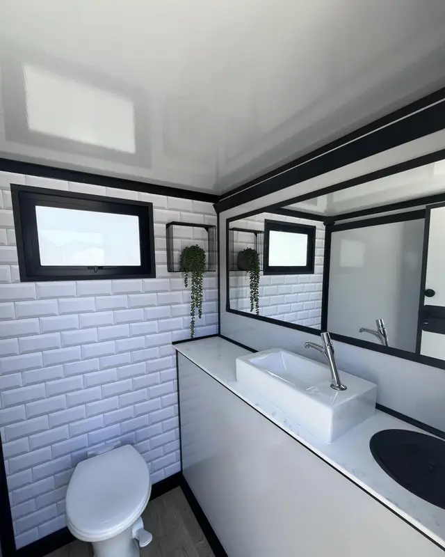 Restroom trailer interior with tile wall, sink and toilet
